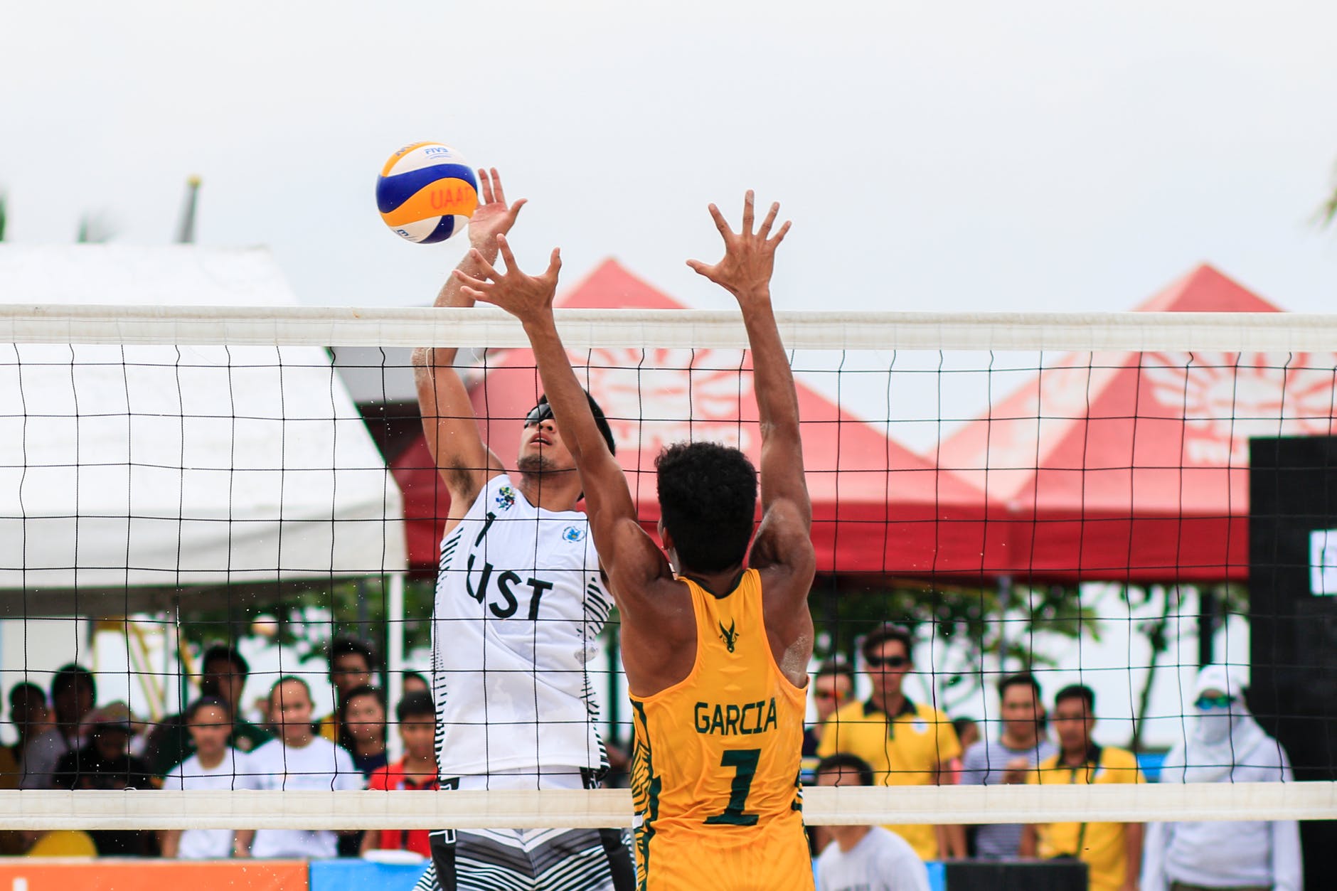 two men playing volleyball near red canopy